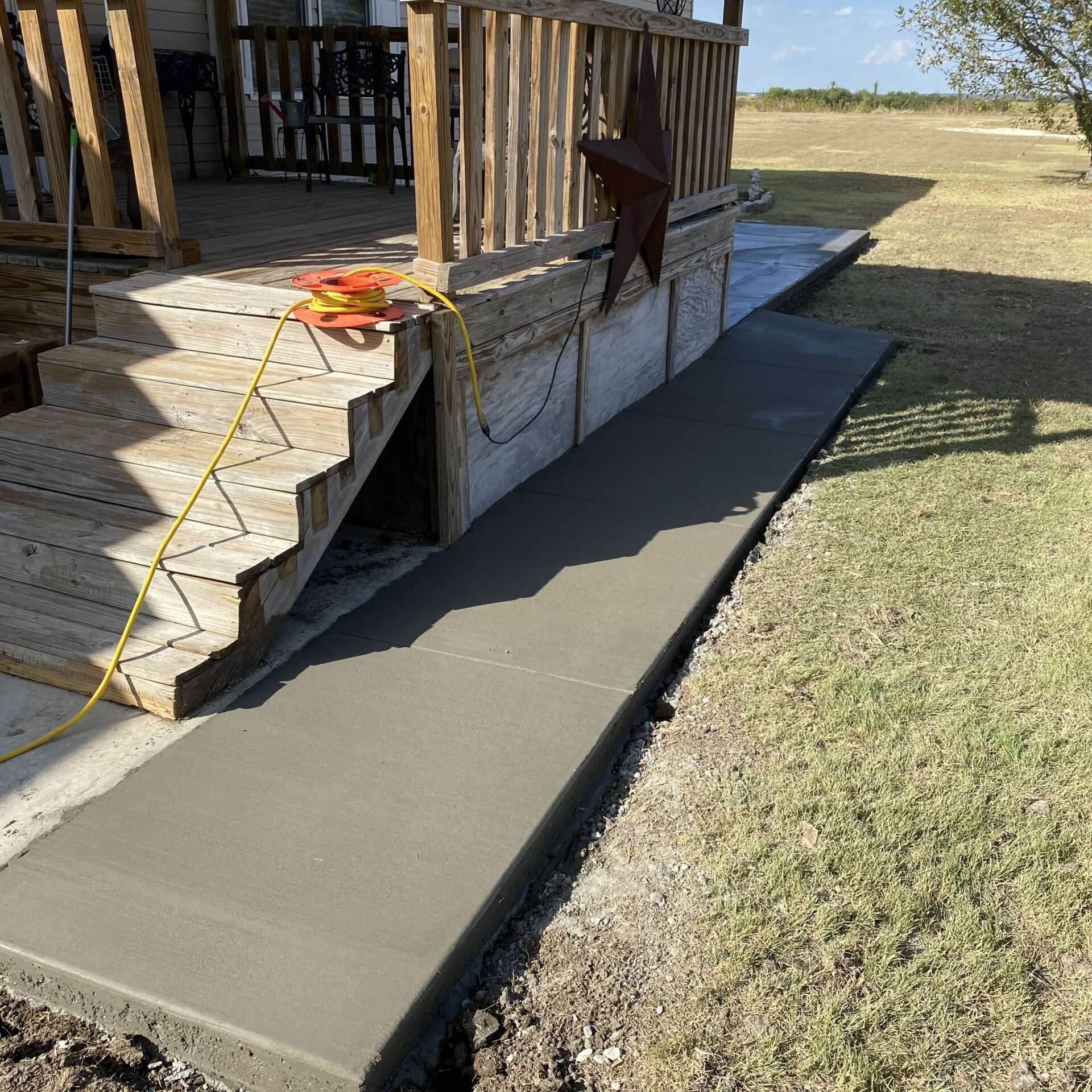 concrete-walkway-installation-covered-porch-central-texas.jpg New concrete walkway installation connecting a covered porch to a backyard patio area at a residential property in Central Texas. concrete stairs installation