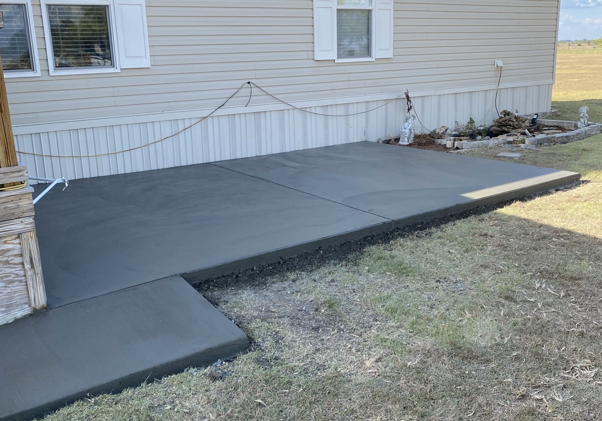 Custom concrete patio and walkway installation completed beside a residential mobile home, creating additional outdoor living and access space in Central Texas.